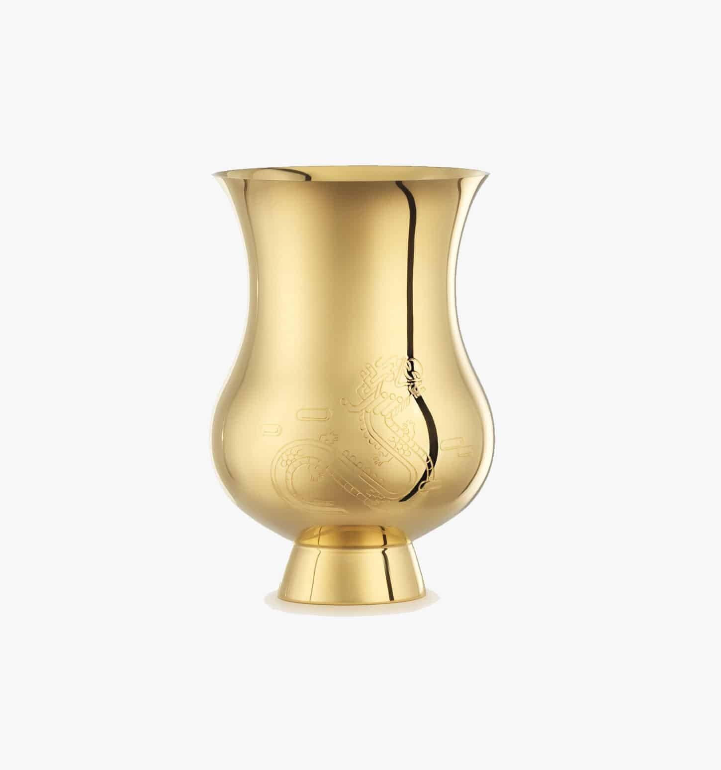 Tumbler engraved with the zodiac sign of the "Year of the Dragon" in vermeil from the Pour le champagne collection by Puiforcat on a light background.